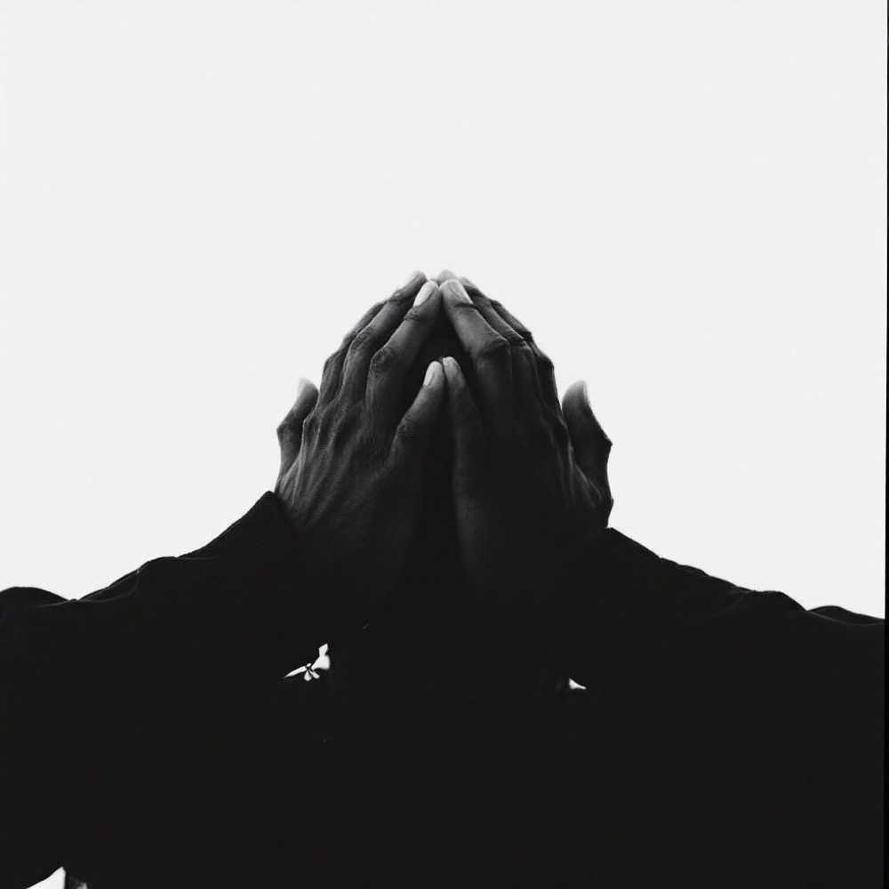 Hands clasped in all black against an infinite white background.